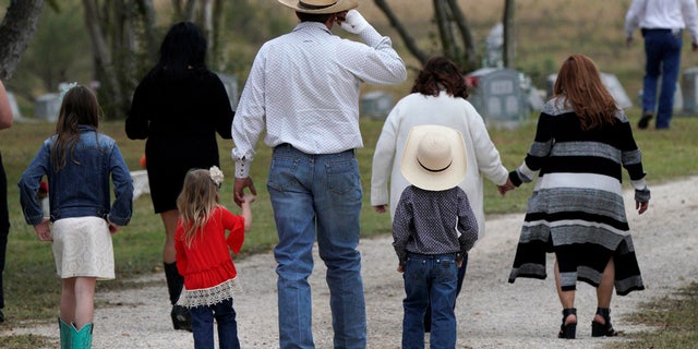 A mourner arrives with his children for the burial of Richard and Therese Rodriguez after the husband and wife were killed in the shooting at First Baptist Church of Sutherland Springs in Texas, Nov. 11, 2017.