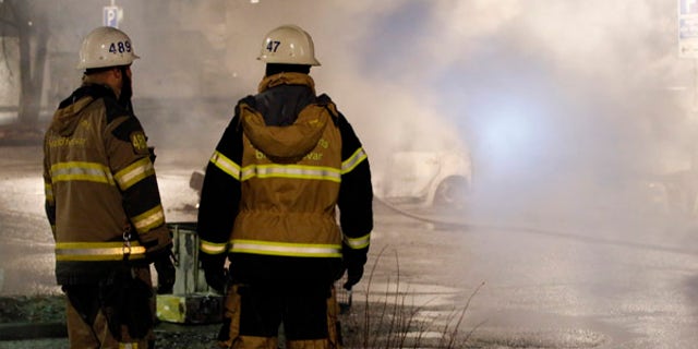Firefighters survey the scene in the suburb of Rinkeby where riots erupted on Monday night.