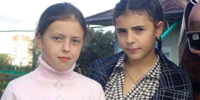 Sept. 11, 2011: 12-year-old Anna, left, and Irina, right, pose in the city of Kopeisk in Russia's Ural Mountains. Two Russian families on Monday won a US$100,000-compensation each from a maternity home that accidentally switched their 12-year old daughters at birth, but they remained at loss about how to fix their shattered lives.