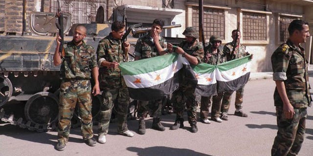 May 12, 2012: Syrian soldiers who defected to join the Free Syrian Army are seen in front of their armoured military vehicle at Khalidieh in Homs.