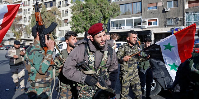 Syrian soldiers wave weapons and national flags in Damascus the morning after the U.S.-led airstrikes.