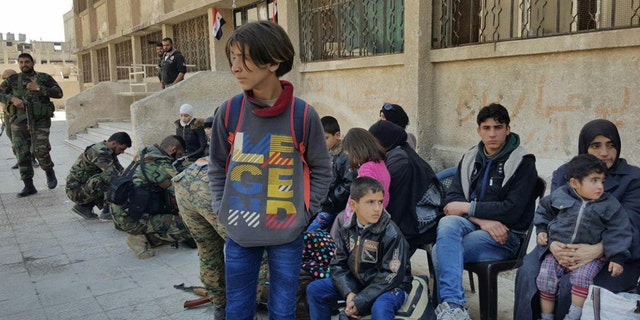 Syrian civilians, who fled fighting between the Syrian government forces and rebels, at an army checkpoint, in eastern Ghouta, a suburb of Damascus, Syria, Tuesday March 13, 2018.