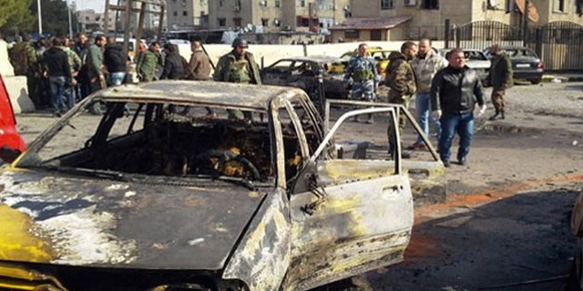 Feb. 9, 2016: In this photo released by the Syrian official news agency SANA, soldiers and plainclothes policemen gather at the scene of an explosion that killed tens of people and wounded others in the Syrian capital of Damascus.