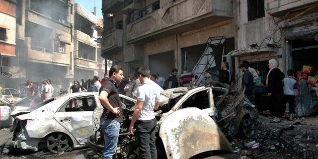 April 29, 2014 - Syrian people gather at the site of one of 2 car bombs that exploded in the pro-government district of Zahra in the central Syrian city of Homs, Syria. Photo provided by Syrian official news agency SANA.