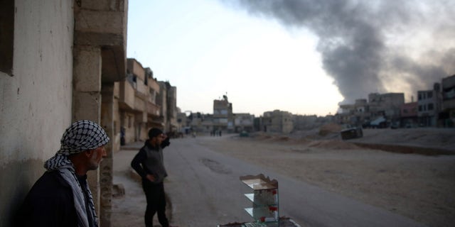Syrian residents watch as smoke rises from Harasta area, as seen from Douma, in the eastern Damascus suburb of Ghouta, Syria November 14, 2017. REUTERS/Bassam Khabieh - RC1B753E7E30