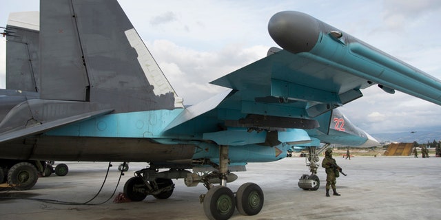 Jan. 20, 2016: A Russian soldier stands guard next to a Su-34 bomber at Hemeimeem air base in Syria.