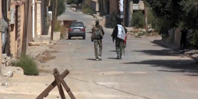 This Saturday, Oct 21, 2017 frame grab from video, shows two Syrian soldiers walking in the street of Qaryatayn, a town in central Syria which was recaptured from Islamic State group militants on Saturday.