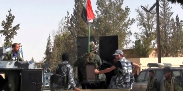 This Saturday, Oct. 21, 2017 frame grab from video, shows Syrian soldiers patrolling in the street of Qaryatayn, a town in central Syria which was recaptured from Islamic State group militants on Saturday.