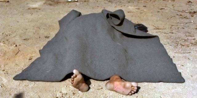 This Saturday, Oct 21, 2017 frame grab from video, shows a body covered with a blanket in the street of Qaryatayn, a town in central Syria which was recaptured from Islamic State group militants on Saturday.