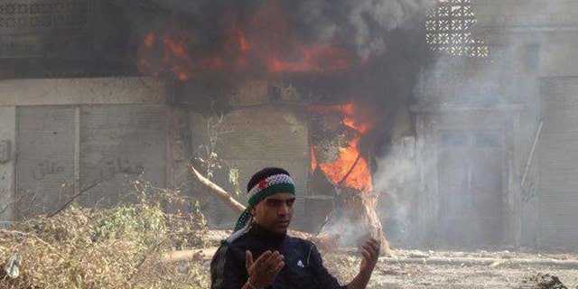 Feb. 12, 2012: In this citizen journalism image provide by the Local Coordination Committees in Syria, an anti-Syrian regime man reacts in front of flames which rise from a burning shop damaged by Syrian government forces shelling, in Baba Amr neighborhood in Homs province, central Syria.