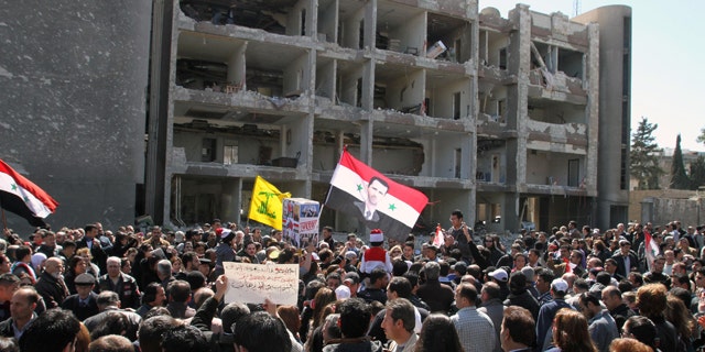 March 18, 2012: Thousands of people wave Syrian flags, one depicting President Bashar Assad, observe a silent march in front of a damaged government building on al-Qassa street in Damascus, Syria in memory of people who were killed a day earlier by two attacks in the capital Damascus. Three suicide bombings in the capital Damascus on Saturday killed several people. The government blamed those on the opposition, which it claims is made up of "terrorist" groups carrying out a foreign conspiracy.