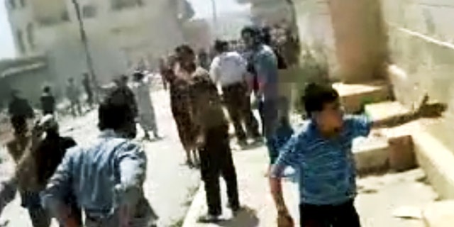 In this image made from amateur video released by the Shaam News Network and accessed Tuesday, May 15, 2012, purports to show Syrians running from gun shots in Khan Sheikhoun, Idlib, Syria.