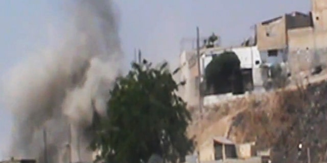 This image made from amateur video released by the Shaam News Network and accessed Wednesday, June 20, 2012, purports to show smoke rising from buildings in Homs province, Syria.