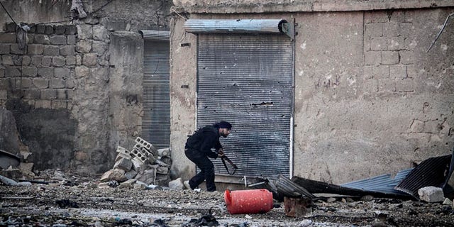 Dec. 5, 2012: A Free Syrian Army fighter runs for cover during heavy clashes with government forces, not pictured, in Aleppo, Syria.