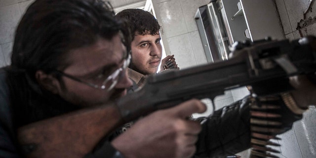 Oct. 28, 2012: In this photo, rebel fighters belonging to the Liwa Al-Tawhid group keep an eye over their enemy's position as they prepare to open fire as mortar explosions and gunshots are heard in the nearby battlefield in the Karm al-Jabel neighborhood of Aleppo, Syria.