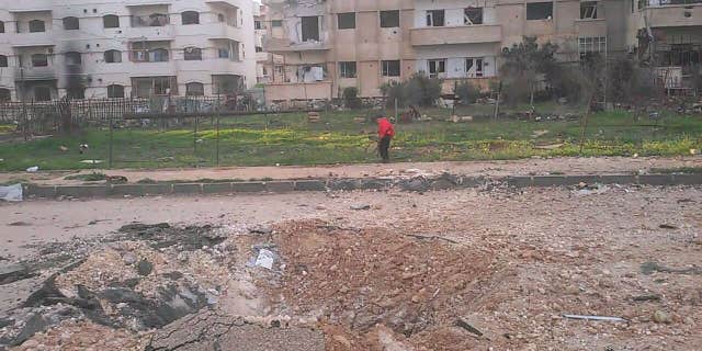 Child plays in remains of a park in Al Waer, Homs in Syria