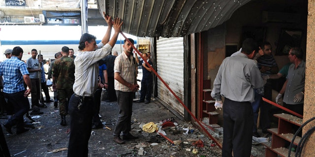 June 11, 2013: In this photo released by the Syrian official news agency SANA, Syrians inspect a damaged shop at a scene of two explosions in the central district of Marjeh, Damascus, Syria. Two explosions hit a central Damascus square Tuesday, killing and wounding dozens of people, activists and the state media reported. State TV said the blasts were caused by suicide bombers, while activists said they were bombs planted there in advance.
