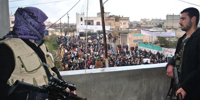 Jan. 27, 2012: Syrian army defectors stand guard on a rooftop to secure an anti-Syrian regime protest in the Deir Baghlaba area in Homs province, central Syria. Armed forces loyal to President Bashar Assad barraged residential buildings with mortars and machine-gun fire, killing at least 30 people, including a family of women and children during a day of sectarian killings and kidnappings in the besieged Syrian city of Homs, activists said Friday.