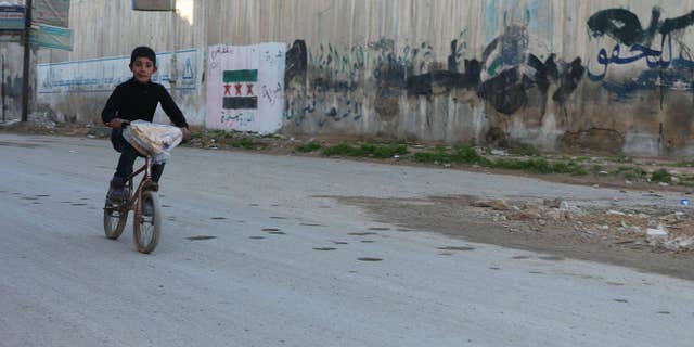 Child rides through the rebel-held streets of the Damascus suburb of Douma, Syria