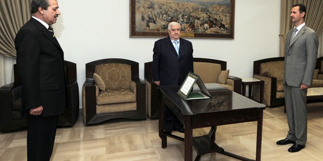 FILE - In this Sept. 16, 2008 file photo provided by the Syrian official news agency SANA, Nawaf Fares, left, is sworn in as Syria's first ambassador to Iraq in 26 years before Syrian President Bashar Assad, right, and Syrian Foreign Minister Walid Moallem in Damascus.
