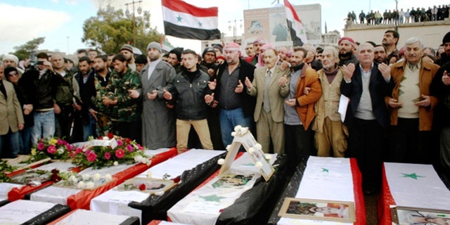 Jan. 23, 2013: In this photo released by the Syrian official news agency SANA, Syrians take part in a funeral procession for those killed in a car bomb explosion at a headquarters of a pro-government militia late Monday in the central town of Salamiya in Hama province, Syria.