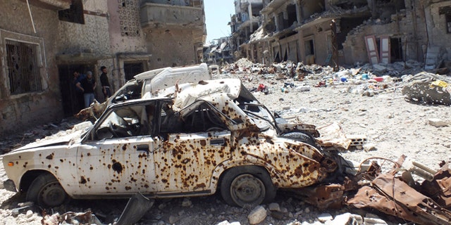 April 28, 2013: A destroyed car is seen on a street lined with buildings damaged by what activists said was shelling by forces loyal to Syria's President Bashar al-Assad in the besieged area of Homs.