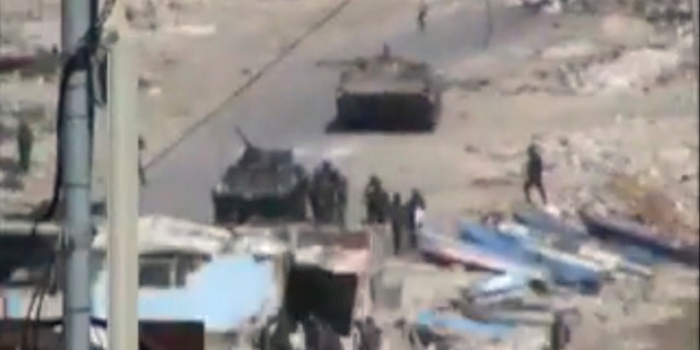 Aug. 17: This image taken from amateur video made available Tuesday purports to show armored vehicles and troops in Latakia, Syria on Monday. Activists say 15 people died in shootings across Syria Monday including at least five in the coastal city of Latakia where military operations where in their fourth day.