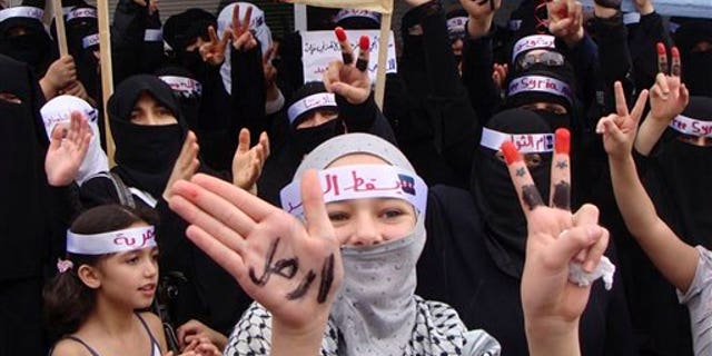 Sept. 30: In this citizen journalism image made on a mobile phone and provided by Shaam News Network, anti-Syrian President Bashar Assad protesters flash V-victory signs as a woman in the foreground displays her hands with the Arabic word reading: "leave", during a demonstration against the Syrian regime, in Edlib province, Syria. Syrian security forces opened fire on protesters Friday as thousands rallied across the country to call for the downfall of President Bashar Assad's regime, activists said.