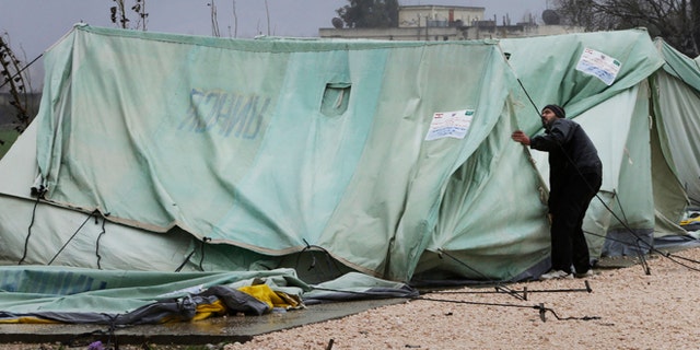 Jan. 7, 2013: A Syrian refugee man, fixes a tent that was blown off by the wind, at a temporary refugee camp in the eastern Lebanese town of Marj near the border with Syria, Lebanon.