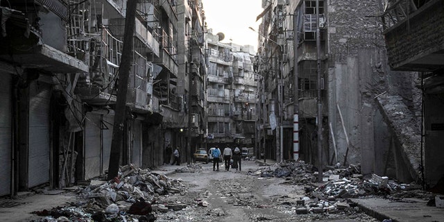 Oct. 27, 2012: In this photo, Syrian residents walk on a street among the debris of buildings damaged by heavy shelling in the southeast of Aleppo City.