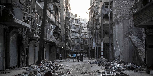 Oct. 27, 2012: In this photo, Syrian residents walk on a street among the debris of buildings damaged by heavy shelling in the southeast of Aleppo City.