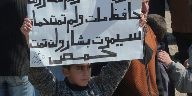 March 2: A boy holds up a placard during a demonstration against Syria's Assad near the city of Homs that reads: 'Nero died, Rome did not die, Hafez died, Hama did not die, Bashar will die, Homs will not die.'