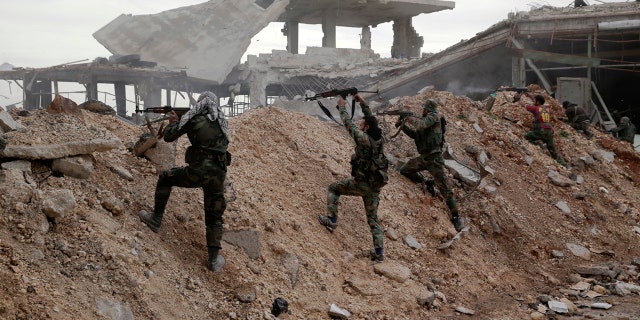 Syrian army soldiers fire their weapons during a battle with rebels at the Ramouseh front line, east of Aleppo, Syria, Monday, Dec. 5, 2016.