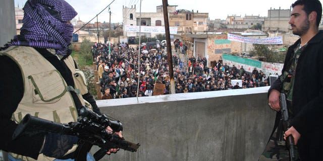 Jan. 27, 2012: Syrian army defectors stand guard on a rooftop to secure an anti-Syrian regime protest in the Deir Baghlaba area in Homs province, central Syria.