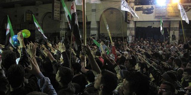 April 4, 2012: In this photo, Syrians raise their hands vowing to continue fighting until President Bashar Assad's regime falls during a protest in a neighborhood in Damascus, Syria.