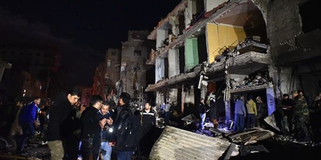 People gather on the street after bombings in Syria in the Sayyida Zeinab area, 6 miles (10 km) south of Damascus, Sunday, Feb. 21, 2016. (AP Photo/Natalia Sancha)