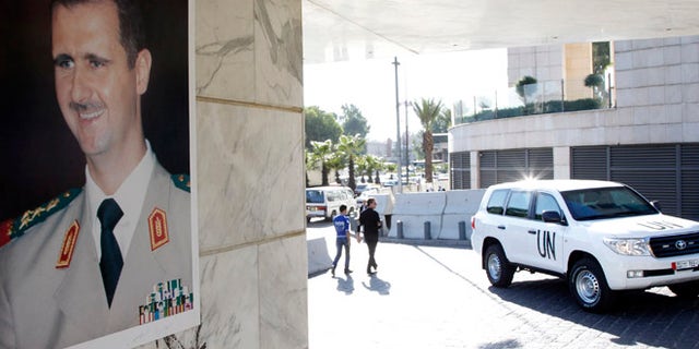 Oct. 8, 2013: A U.N. vehicle is seen near a photo of Syrian President Bashar al-Assad at the entrance of a hotel where a team of experts from the Organisation for the Prohibition of Chemical Weapons (OPCW) were staying in Damascus. (Reuters)
