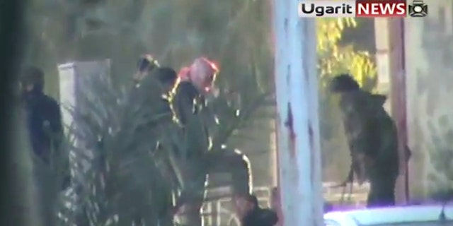 Dec. 12: This image from amateur video made available by the Ugarit News group purports to show a man being kicked by a group of soldiers in Hama, Syria.