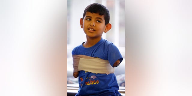 In this Friday, Dec. 18, 2015, photo Syrian refugee Ahmad Alkhalaf, 9, talks with his father and sponsors at a mosque in Sharon, Mass. Ahmad, who arrived in the Boston area this past summer for medical treatment, said he used to have restless nights when he would relive his mothers screams from the night a bomb killed three of his siblings and left him without arms. But those sounds, he said, have largely faded. (AP Photo/Stephan Savoia)