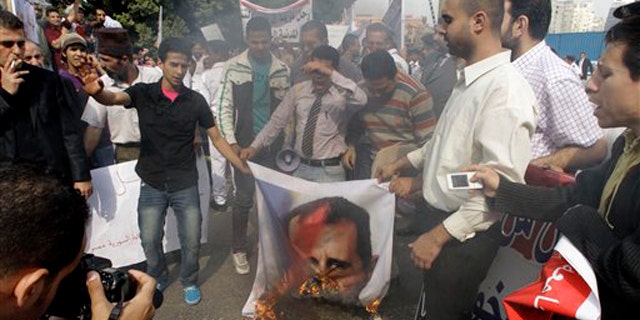 Syrian protesters burn a picture of Syrian President Bashar Assad during a protest in front of the Arab League headquarters in Cairo, Egypt, Saturday, Nov.12, 2011.