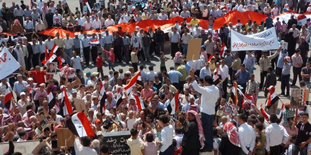 July 13: Syrian pro-government protesters carry national flags and banners as they call for a reform program and in support of the national unity in the city of Sanamein, in the southern city of Daraa, Syria.