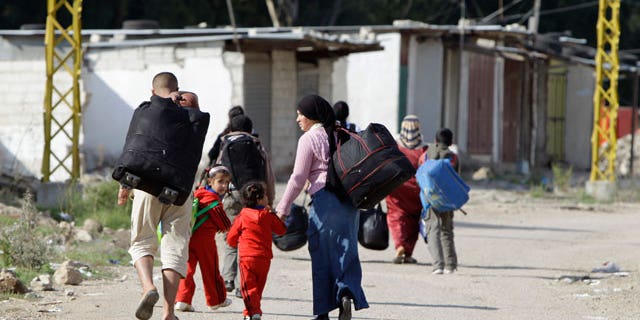 Oct. 31, 2011: Syrian citizens carry their belongings as they cross the Lebanon- Syria border illegally to return to Syria, from the village of Arida, north Lebanon.