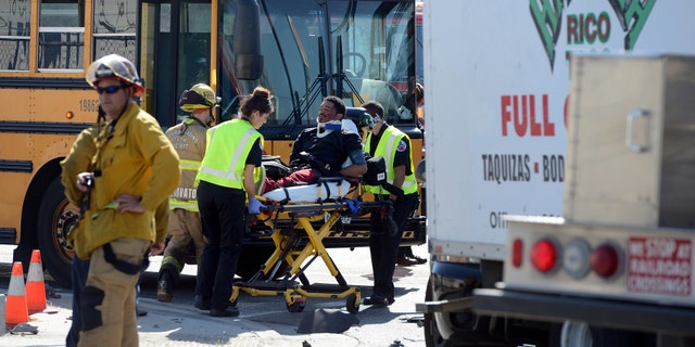 A man is transported to an ambulance at the scene of an accident involing a stolen taco truck and a school bus.