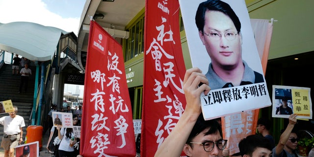 In this Sept. 11, 2017, file photo, a protester raises a picture of Taiwanese activist Lee Ming-che during a demonstration outside the Chinese liaison office in Hong Kong.