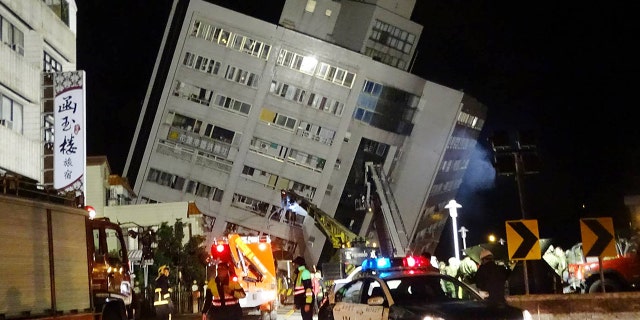 Rescuers are seen entering a building that collapsed onto its side from an early morning 6.4 magnitude earthquake in Hualien County, eastern Taiwan.