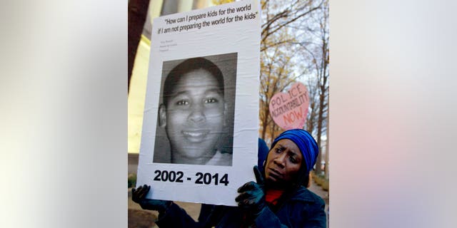 A woman holds up a picture of Tamir Rice, 12, who was fatally shot by a police officer in Cleveland, Ohio.