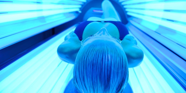 young woman at laying on solarium bed and get brown skin tone ready for summer