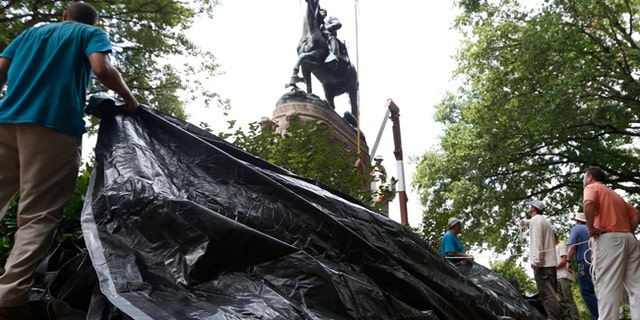City workers prepare to drape a tarp over a statue of Confederate General Stonewall Jackson in Charlottesville, Va., Aug. 23, 2017.