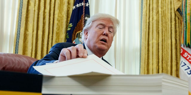 President Trump signed the tax bill in the Oval Office just before leaving Washington for the holidays.