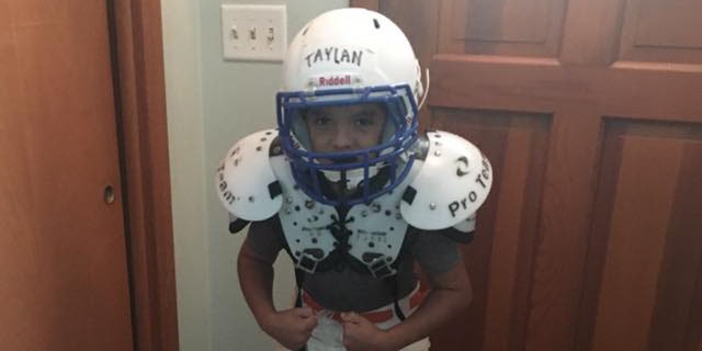Taylan flexes his muscles in his football gear.